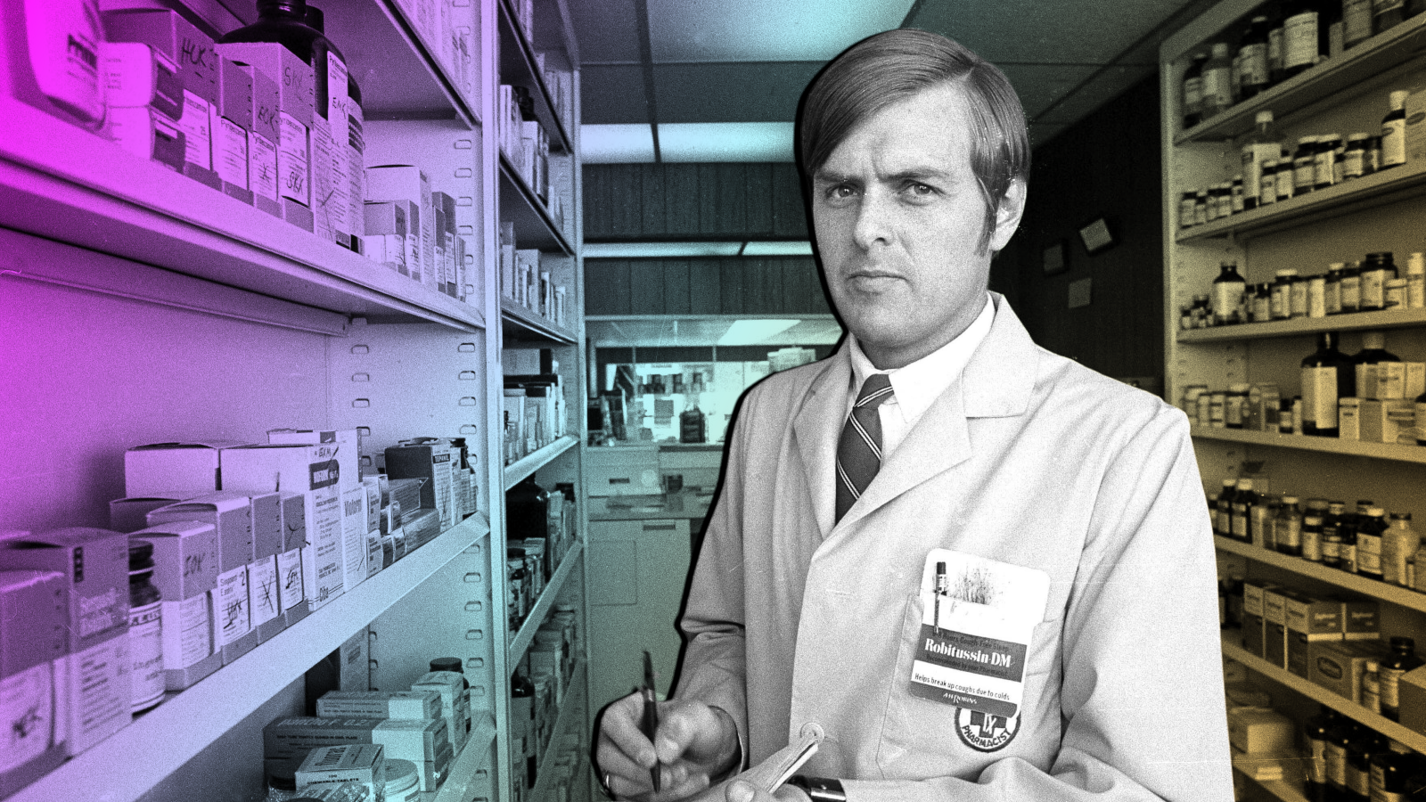 A pharmacist stands with pen and pad in hand in front of shelves of drugs.