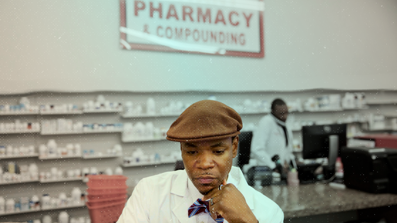 An independent pharmacy owner, in a hat and lab coat, works at his pharmacy in East Atlanta, GA.