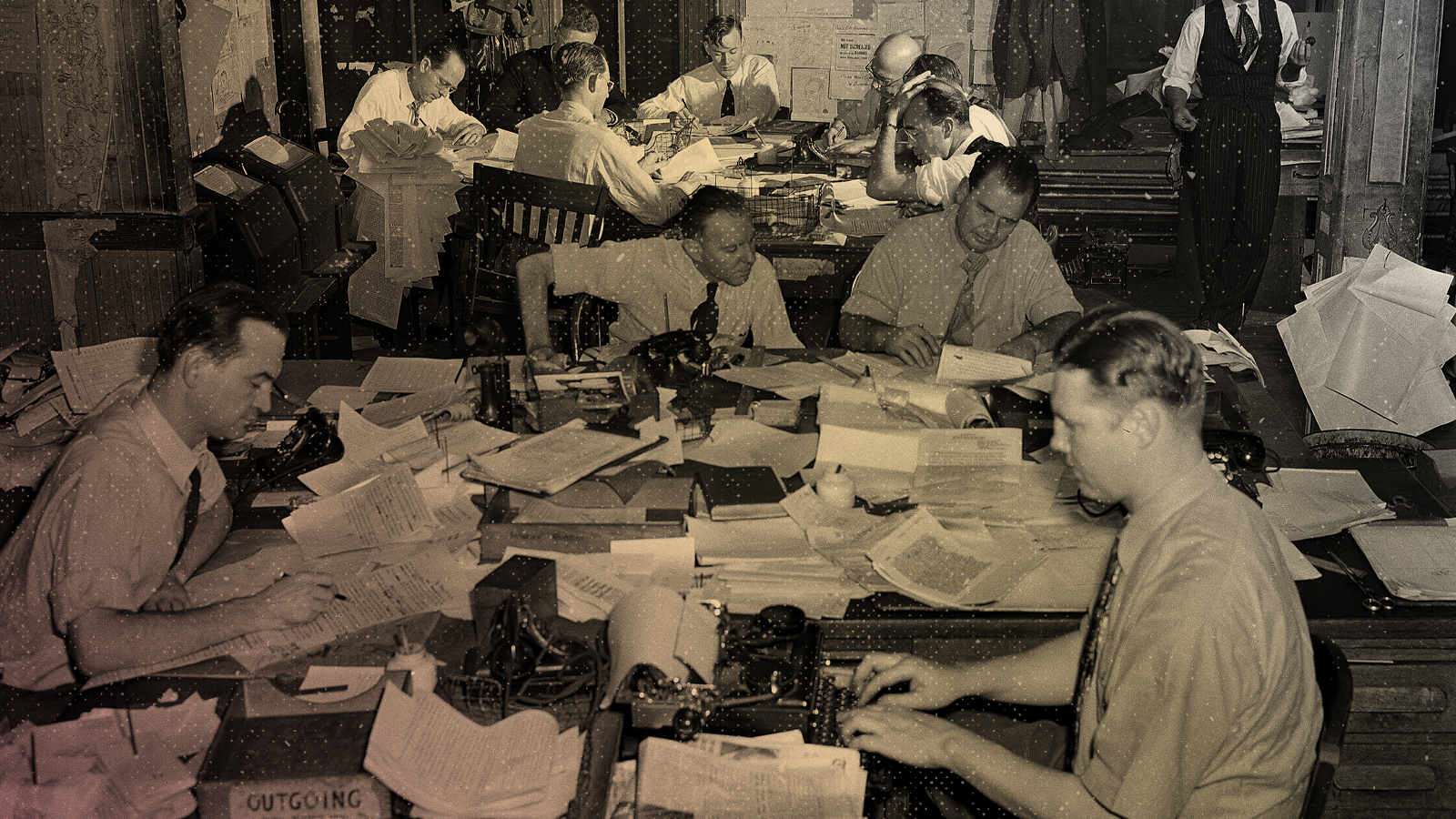 A black and white photo of journalists and editors hard at work in an old newsroom circa 1947.
