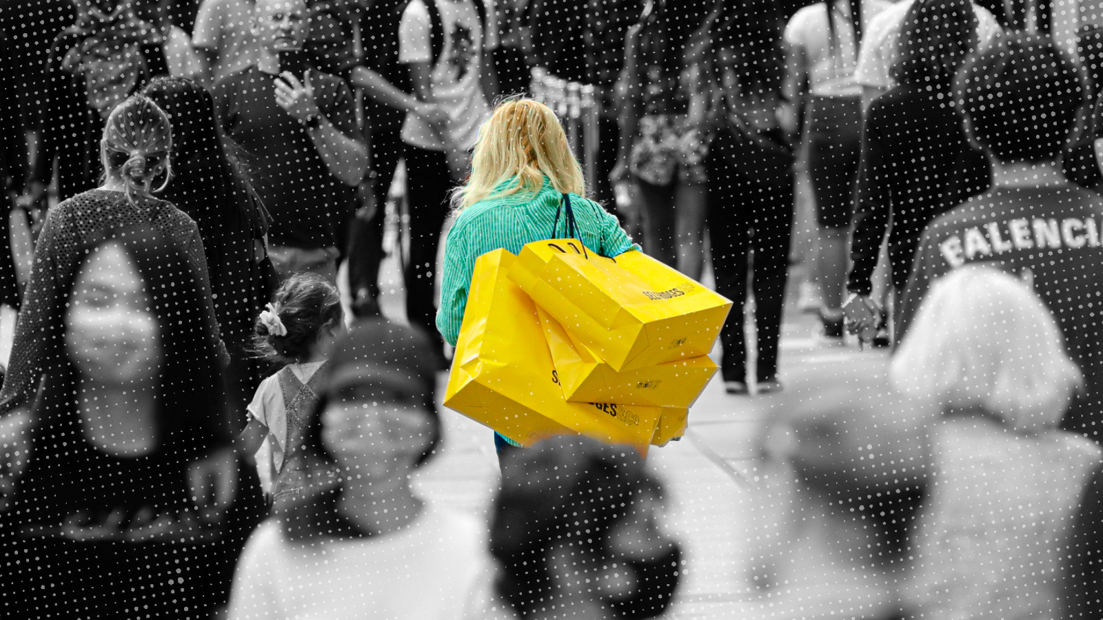 A crowd of shoppers in the street with a woman in the center highlighted holding large yellow shopping bags.