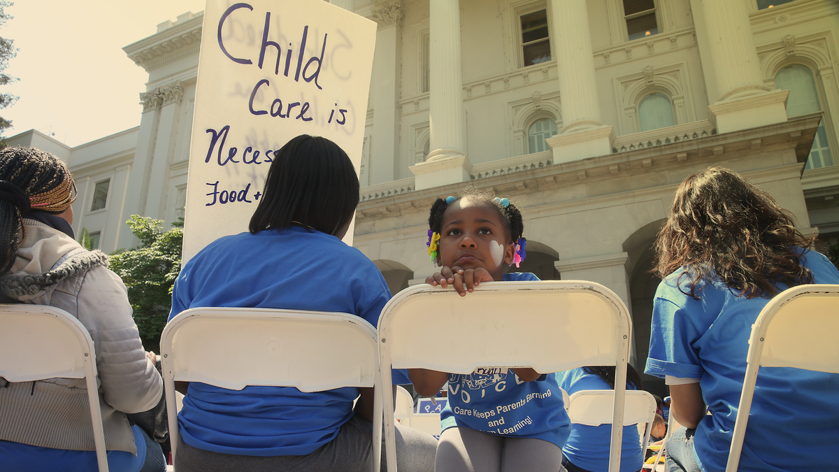 A family sits at a rally calling for increased child care subsidies at the Capitol in Sacramento, California.