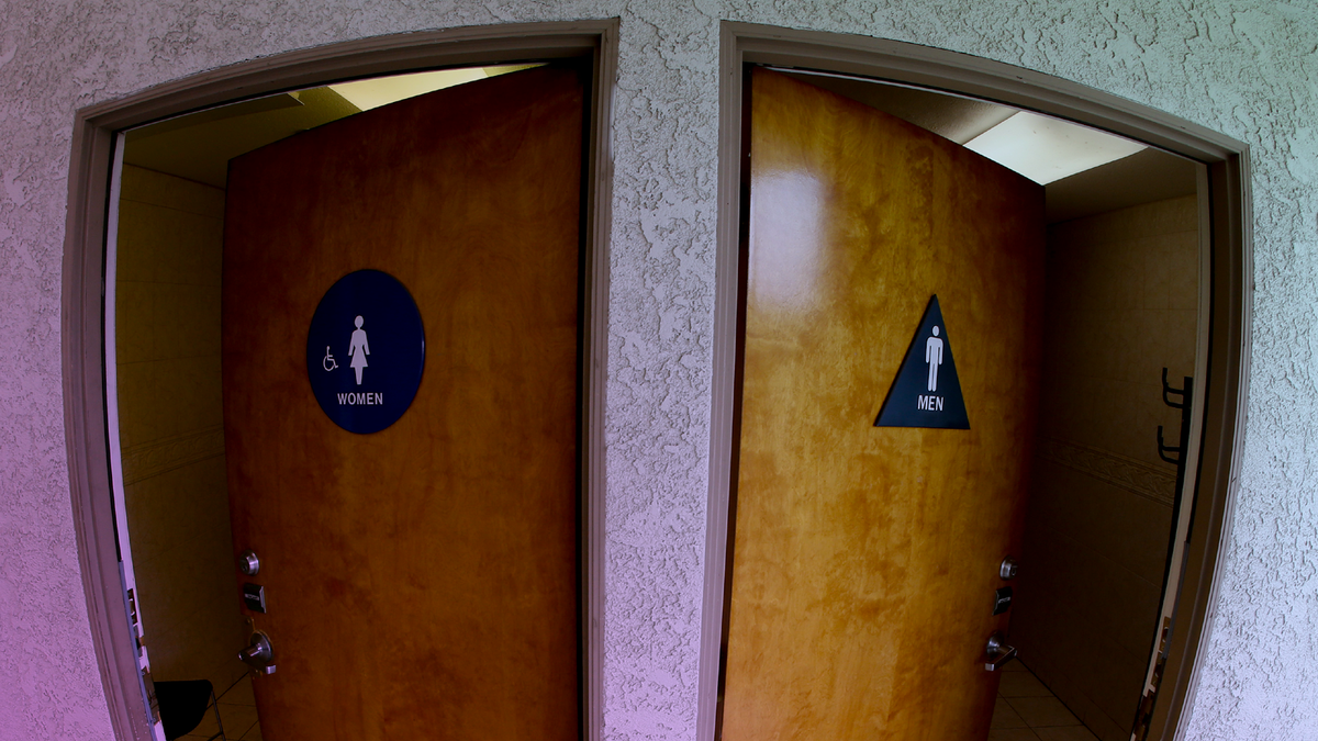The doors to public restrooms are propped open at a office complex, one with a sign for women and one with a sign for men.