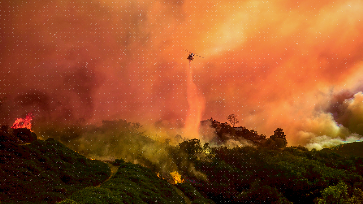 A helicopter drops water on the Palisades Fire in Los Angeles on January 7, 2025. (AP Photo/Ethan Swope)